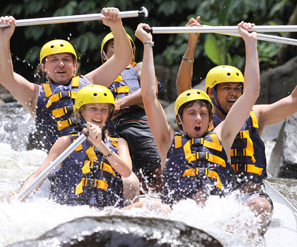 A group of men and woman play white water rafting in Bali river